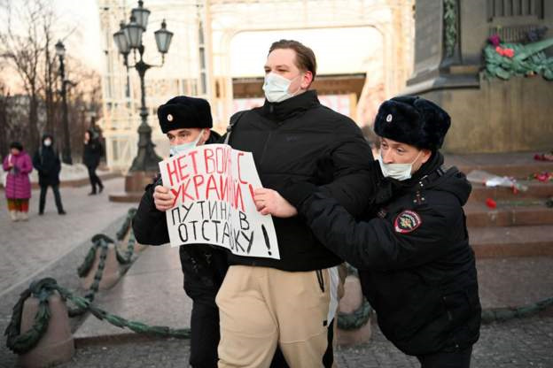 A Russian protestor being led away by police, likely in Moscow. Retrieved from unknown, but likely the BBC.