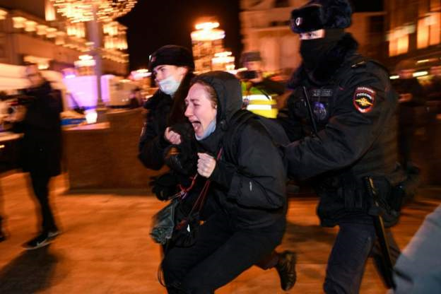 A Russian protestor being led away by police, likely in Moscow. Retrieved from unknown, but likely the BBC.